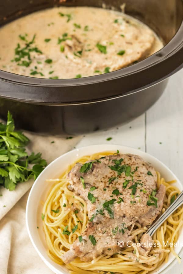 Crock-Pot ranch pork chops on a plate with noodles and in a crock pot