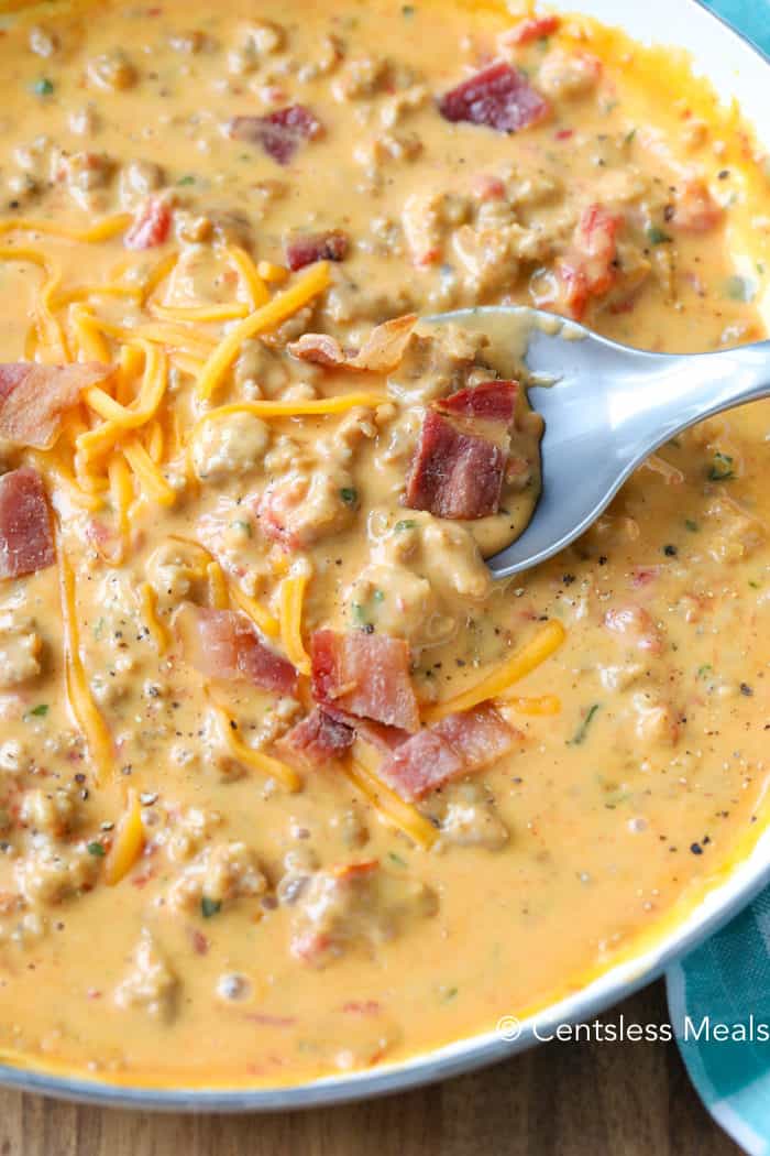 Bacon cheeseburger dip in a white bowl with a spoonful being taken out