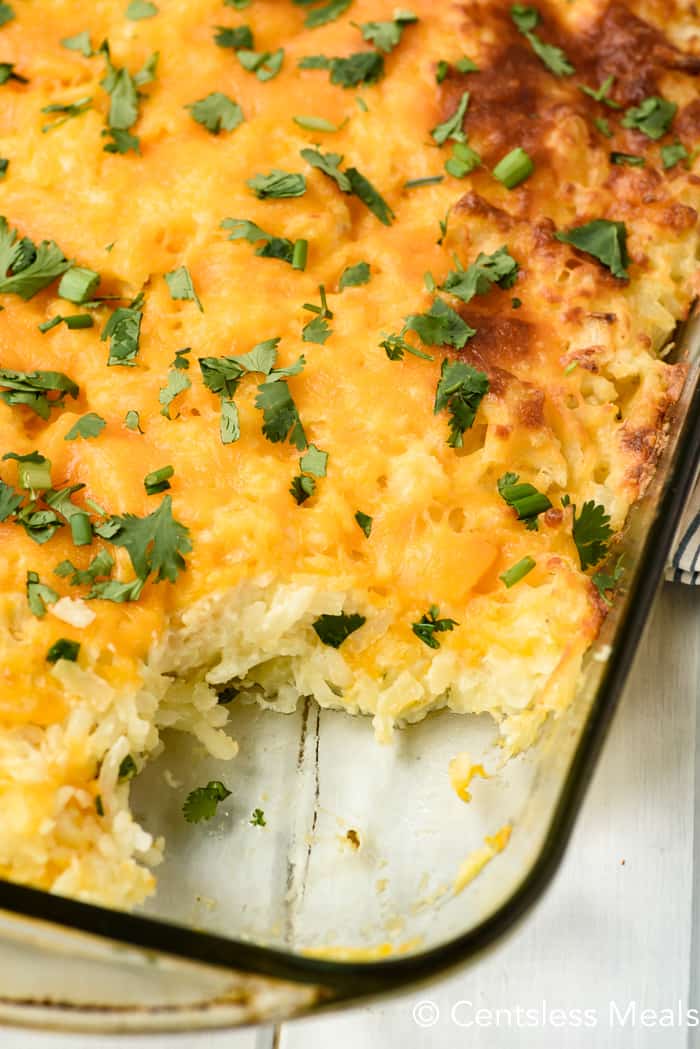 Hashbrown casserole in a clear casserole dish with a scoop taken out
