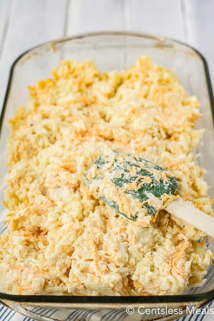 Hashbrown casserole in a casserole dish with a rubber spatula