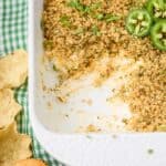 Jalapeno popper dip in a white casserole dish with a scoop taken out