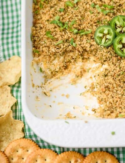 Jalapeno popper dip in a white casserole dish with a scoop taken out