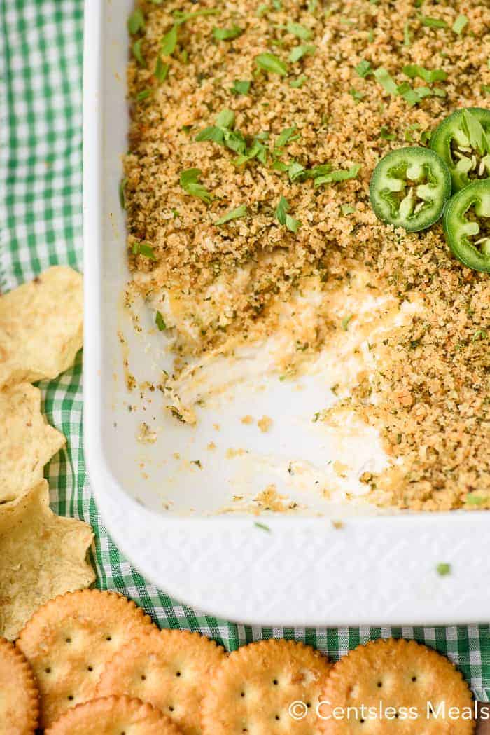 Jalapeno popper dip in a white casserole dish with a scoop taken out