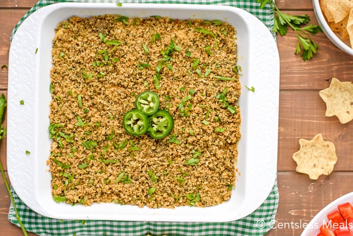 Jalapeno popper dip in a white casserole dish with jalapenos and cilantro