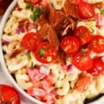 Bacon ranch macaroni salad in a white bowl topped with bacon and tomatoes