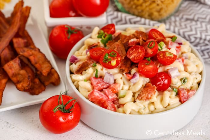 Bacon ranch pasta salad in a white bowl with tomatoes and bacon on the side