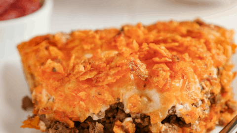 Slice of Doritos pie on a white plate with a bite taken out