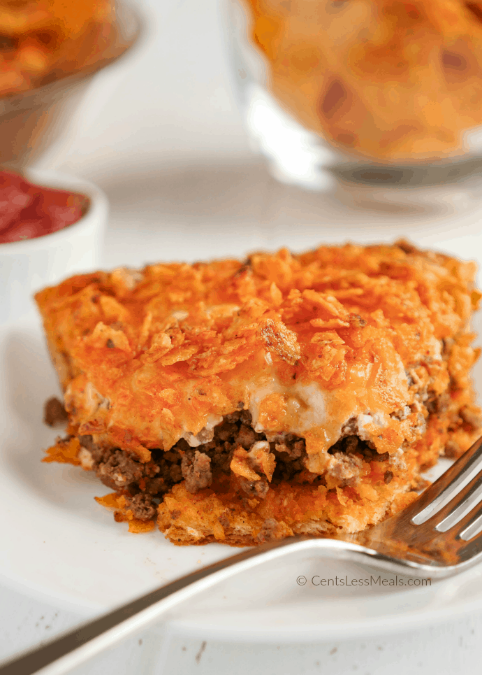 Slice of Doritos pie on a white plate with a bite taken out