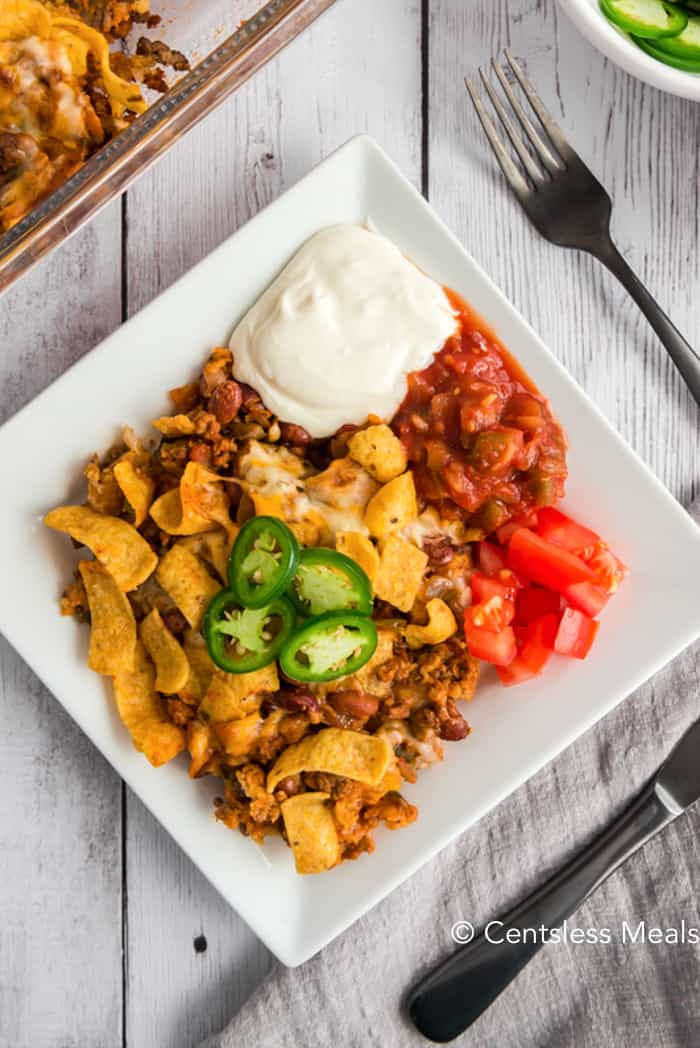 Frito pie on a plate with jalapenos tomato salsa and sour cream