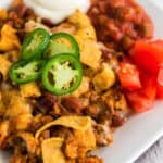 Frito pie on a plate topped with jalapenos