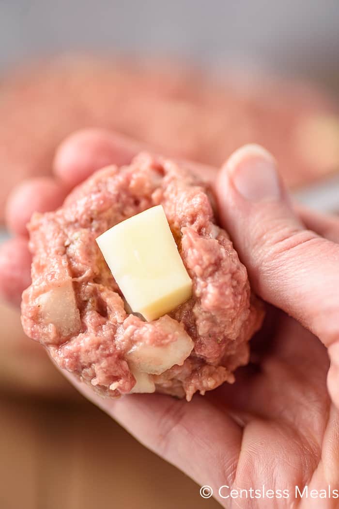 Raw meatloaf with a cube of mozzarella cheese