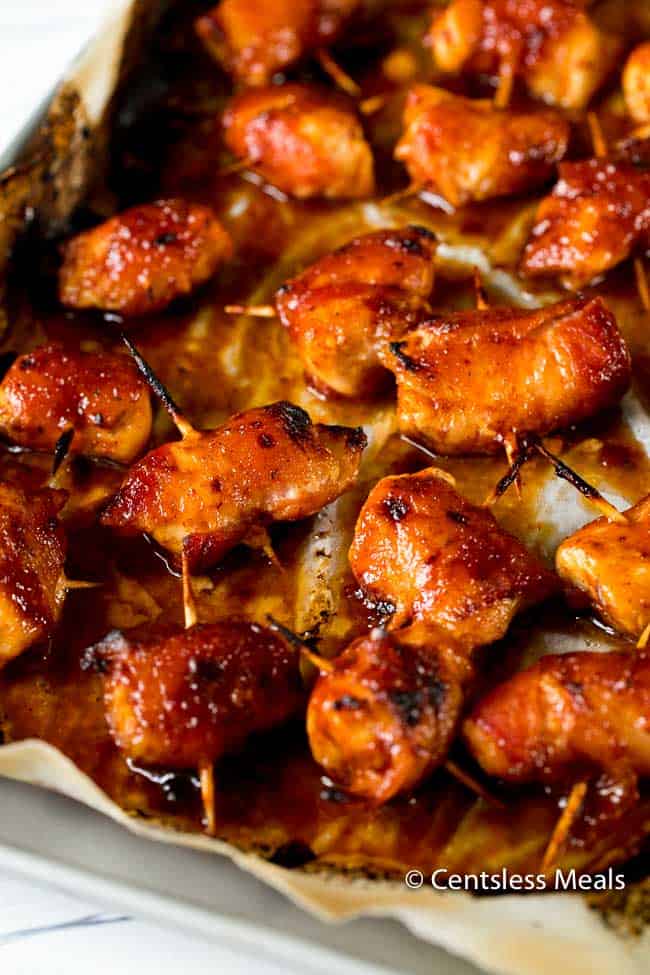 BBQ bacon wrapped chicken bites on parchment paper with toothpicks