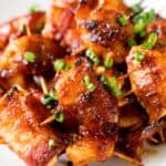 BBQ bacon wrapped chicken bites on a plate garnish with green onions