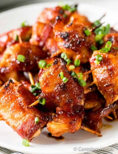 BBQ bacon wrapped chicken bites on a plate garnish with green onions