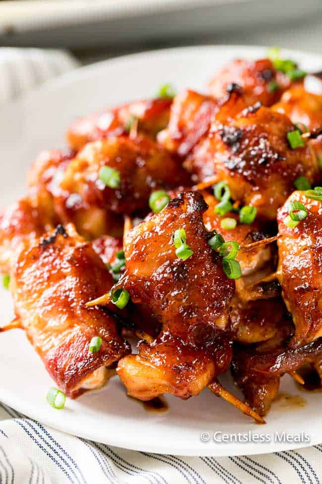 Bacon chicken BBQ bites on a plate garnished with green onions