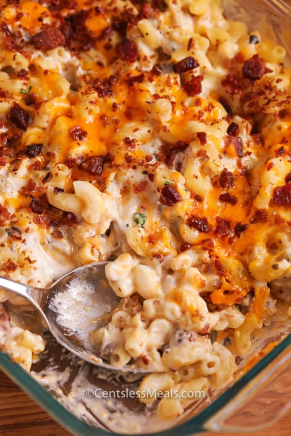 Bacon chicken macaroni and cheese in a clear casserole dish with a spoonful being taken out
