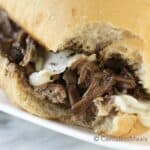 Crock-Pot Italian beef sandwich on a white plate with a bite taken out