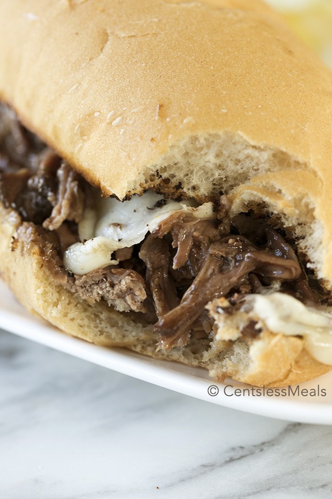 Crock-Pot Italian beef sandwich on a white plate with a bite taken out