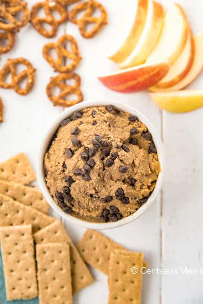 Edible cookie dough on a wooden board with crackers apples and pretzels