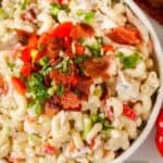 Ranch macaroni salad with bacon and chicken in a bowl topped with green onion bacon and tomato