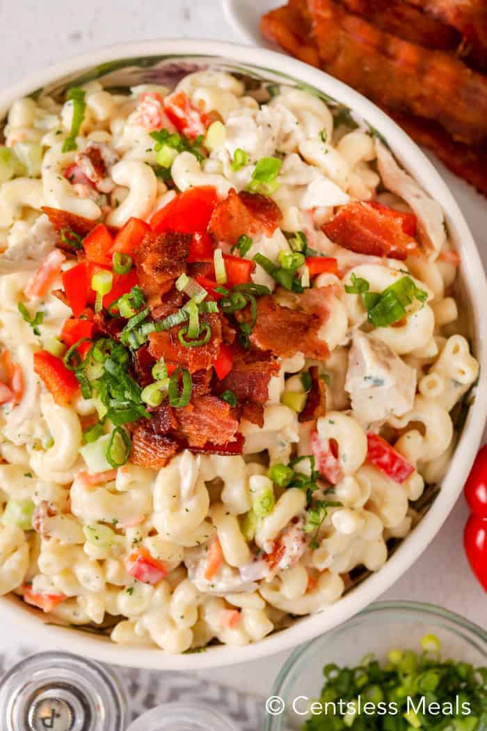 Ranch macaroni salad with bacon and chicken in a bowl topped with green onion bacon and tomato