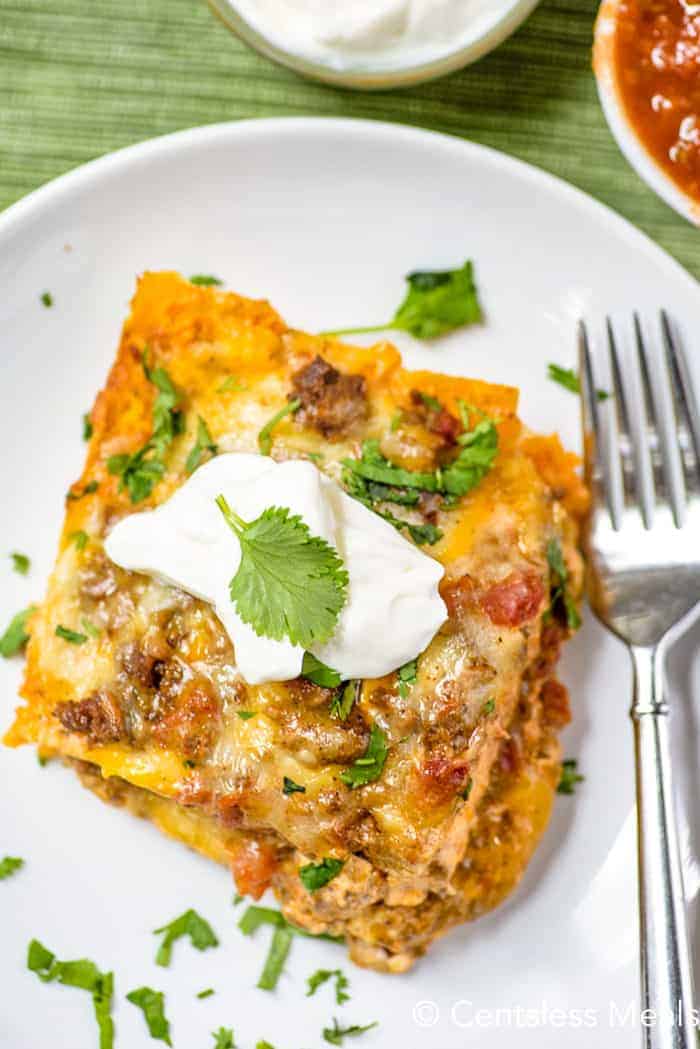 Taco bake on a white plate with a fork and cilantro