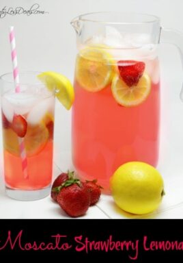 Moscato strawberry lemonade in a glass and in a glass pitcher with strawberries and lemon on the side