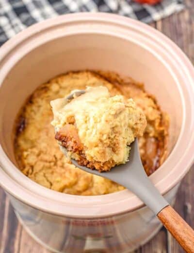 Crock pot apple cobbler in a crock pot with a spoonful taken out