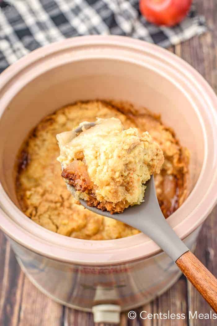 Crock pot apple cobbler in a crock pot with a spoonful taken out