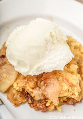 Crock pot apple cobbler on a white dish topped with ice cream
