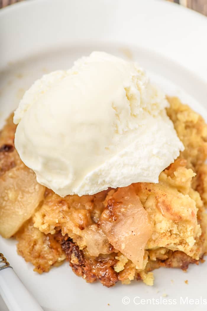 Crock pot apple cobbler on a white dish topped with ice cream