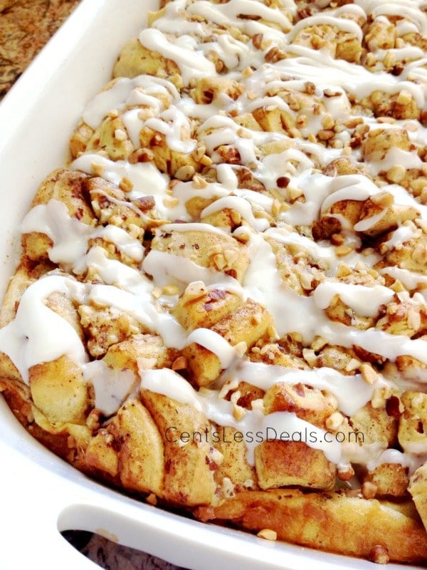Cinnamon roll french toast casserole in a white dish drizzled with icing