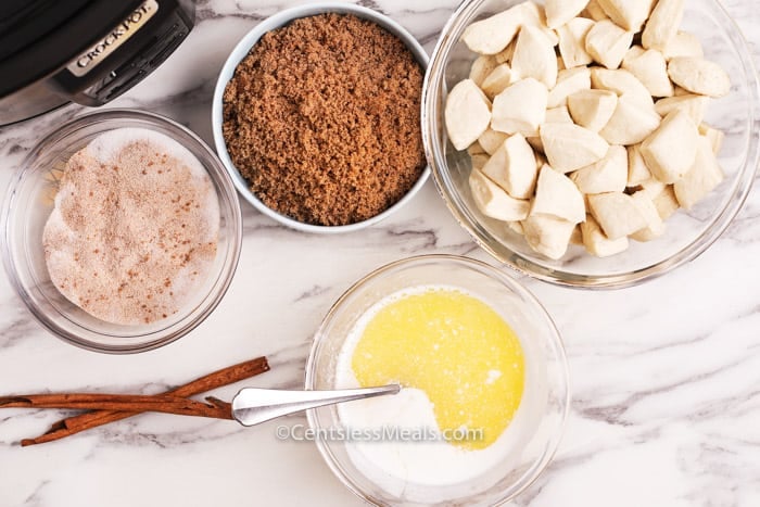 Ingredients for Crock-Pot monkey bread on a marble board in glass bowls