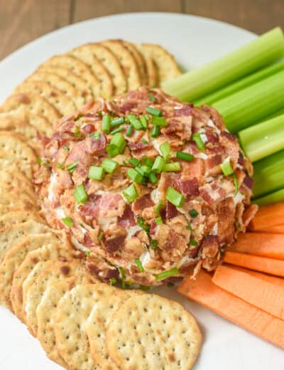 Bacon Ranch Cheeseball on a plate with crackers, celery and carrots