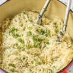 garlic pasta in a pot with parsley and tongs