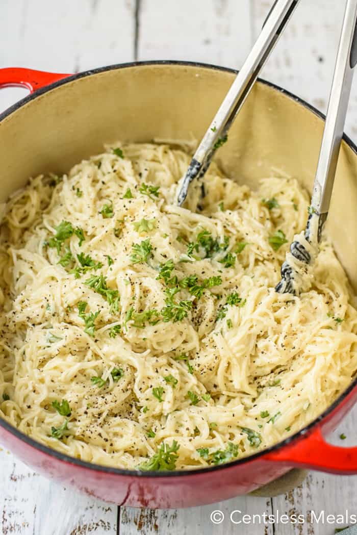 garlic pasta in a pot with parsley and tongs