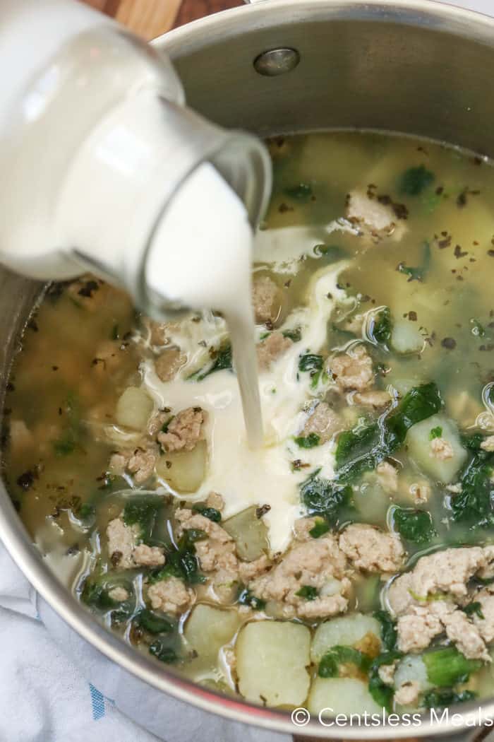 Zuppa Toscana soup in a pot with milk being poured in