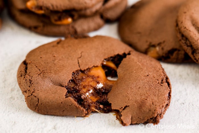 Caramel chocolate cake mix cookies on a marble board with one broken apart to see the inside