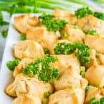 Crab and cheese filled crescent rolls on a white plate with parsley and green onions