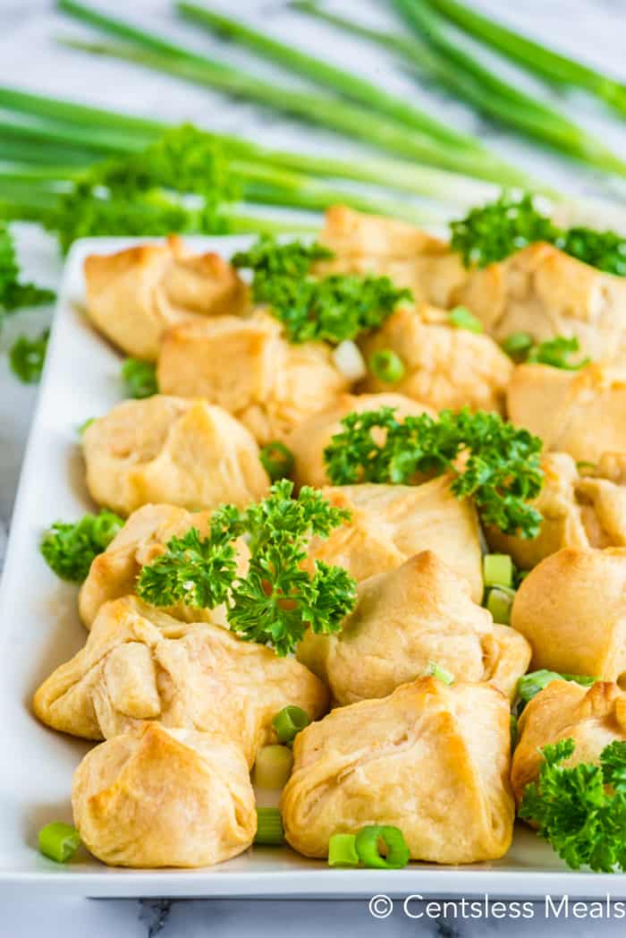 Crab and cheese filled crescent rolls on a white plate with parsley and green onions