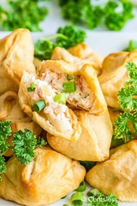 Crab and cheese filled crescent rolls on a plate with parsley and green onions