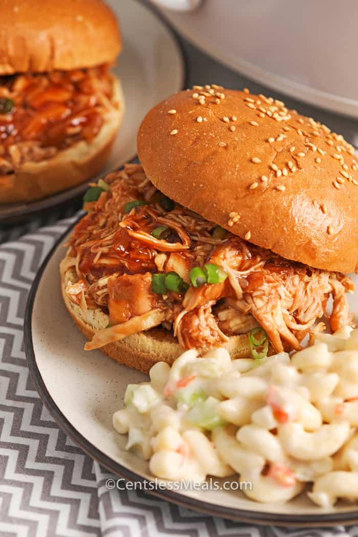 Crock-Pot BBQ beer chicken sandwiches on plates garnished with green onion