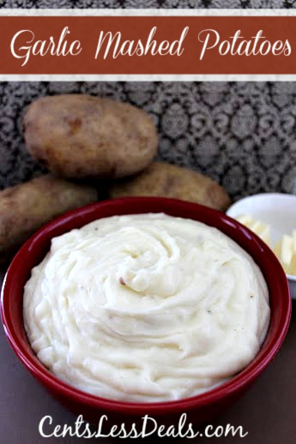 Garlic mashed potatoes in a bowl with butter and potatoes in the background with a title