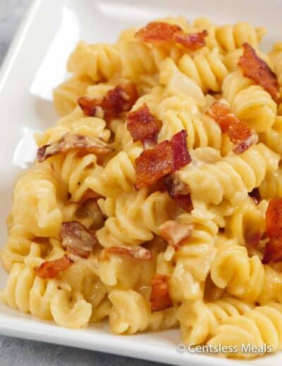 Beer macaroni and cheese on a white plate with bacon
