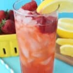 Red Robin's freckled strawberry lemonade in a glass with strawberries and lemon on the side