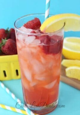 Red Robin's freckled strawberry lemonade in a glass with strawberries and lemon on the side
