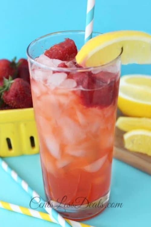 Red Robin's freckled strawberry lemonade in a glass with strawberries and lemon on the side