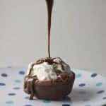 Brownie with ice cream on a plate with chocolate sauce being poured on