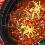 Crock-Pot taco chili in a crock pot topped with shredded cheese tomatoes and green onions