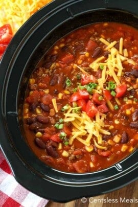 Crock-Pot taco chili in a crock pot topped with shredded cheese tomatoes and green onions